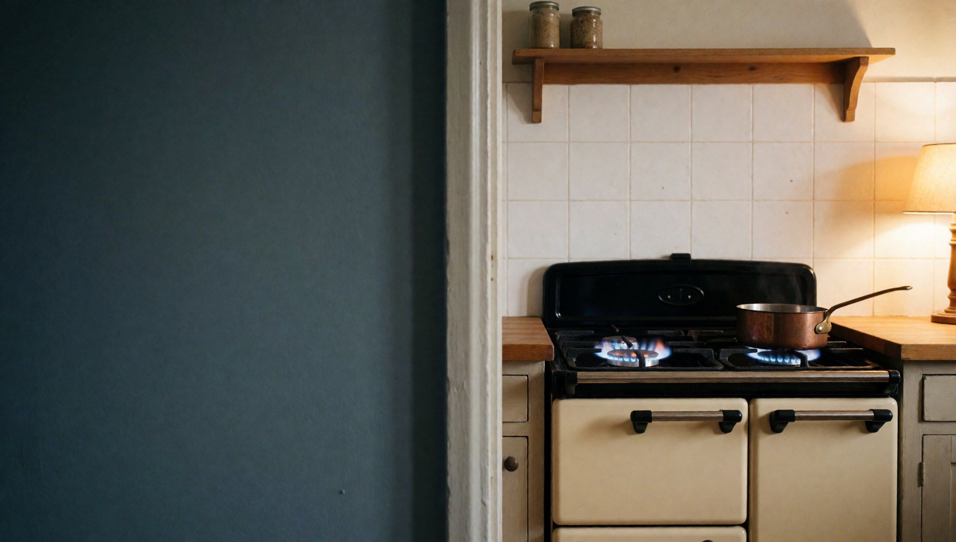 A cream range-style gas cooker in a warm kitchen, with two burners lit with clean blue flames and a copper saucepan on the back.